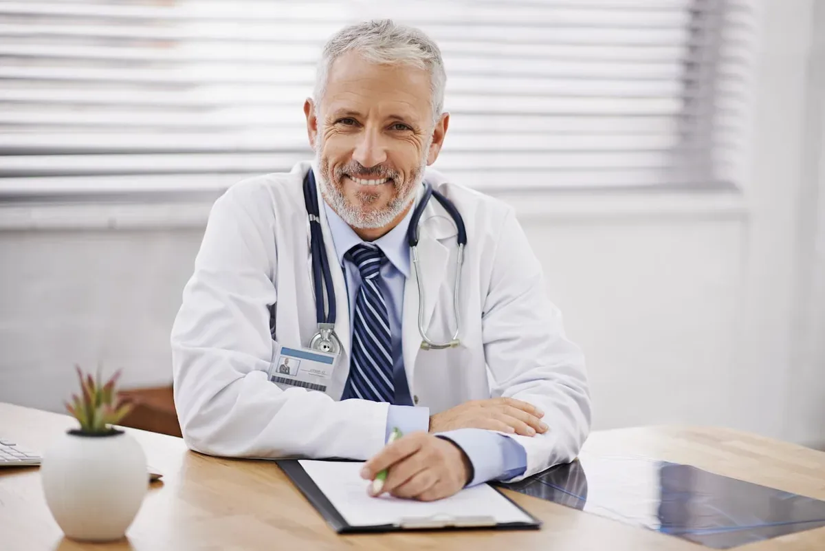 Smiling physician in a white coat at his desk