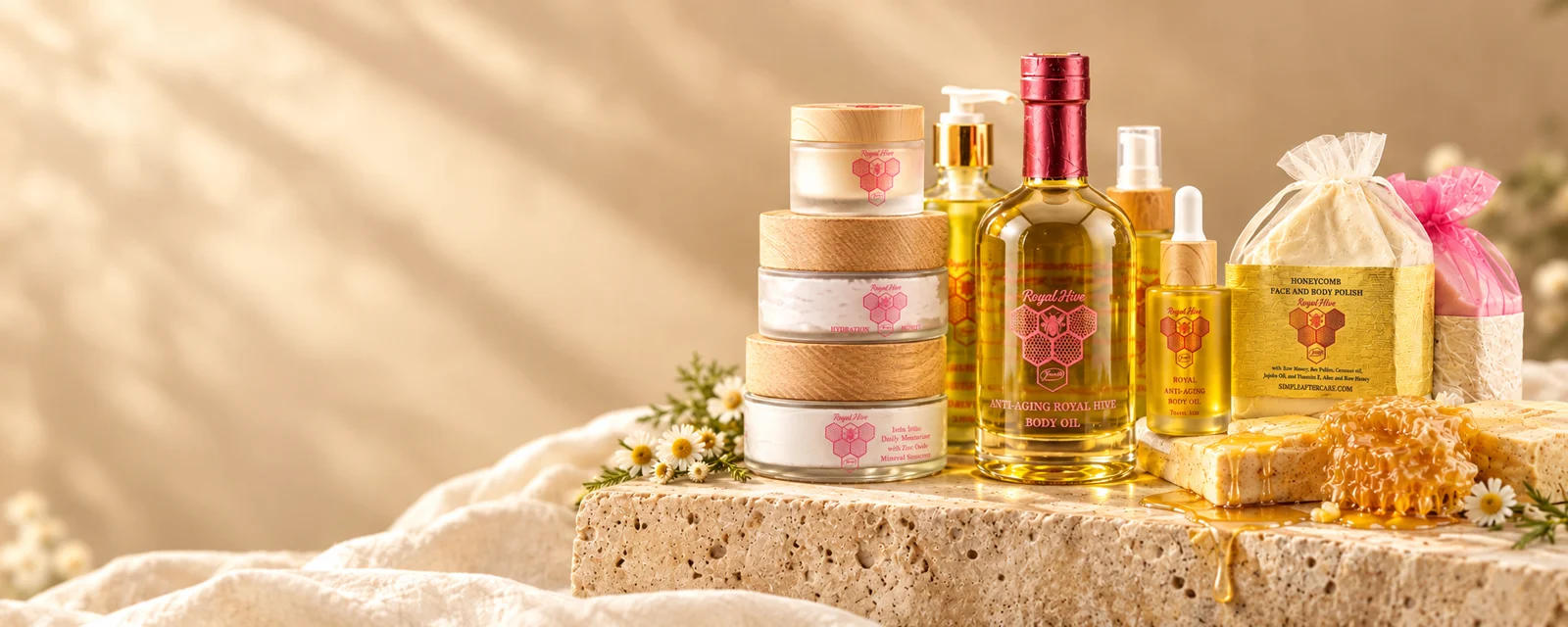 Royal Hive Skincare collection of moisturizers, body oil, honeycomb balm and facial polish on travertine with honeycomb
